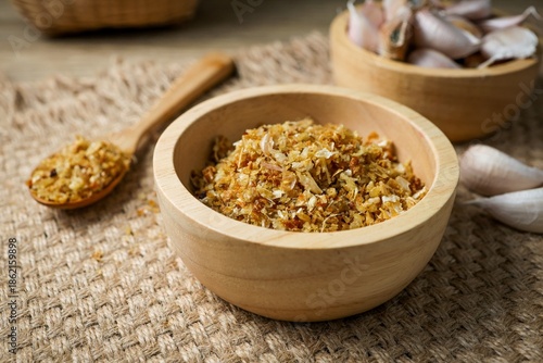 Crispy fried garlic in a wooden bowl on a rustic sackcloth background.
