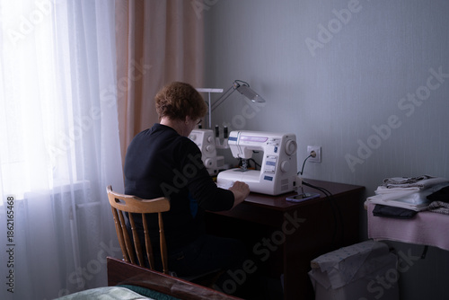 Elderly woman sewing clothes at home