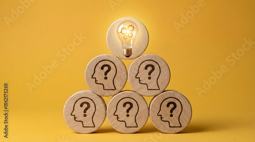 Wooden block pyramid with lightbulb on top and question marks below,representing leadership guidance,problem solving,innovative business idea,finding solution,and mentorship role.