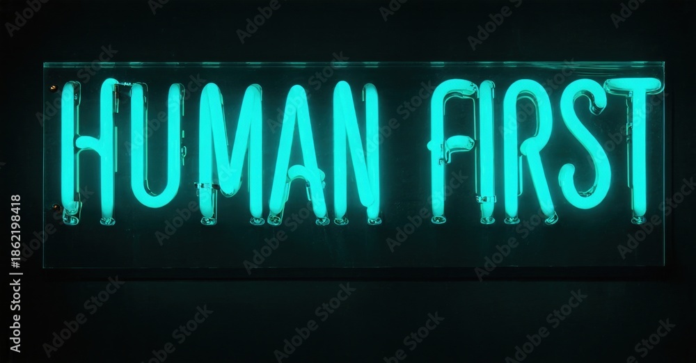 Obraz premium Bright neon sign displays words Human First. Dark background emphasizes glowing turquoise lettering. Simple, direct message.