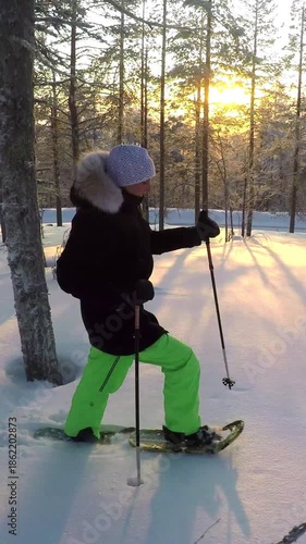 CLOSE UP: Young woman walking through deep snow blanket with snowshoes in Lapland forests. Girl snowshoeing in fresh powder snow at winter sunset. People exercising in fun snowy winter at sunrise