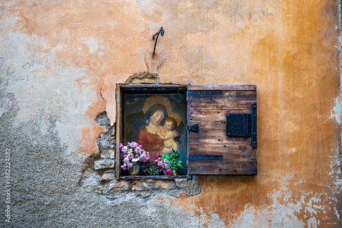mall wall shrine depicting the Virgin Mary and the Child Jesus on a historic stone façade in the medieval center, in Volterra, province of Pisa, Tuscany region, Italy.