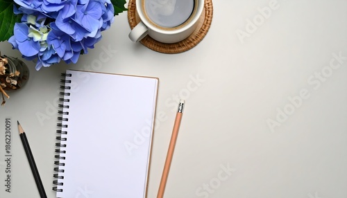 Workspace with notebook, coffee, and blue hydrangea flowers for creative inspiration.