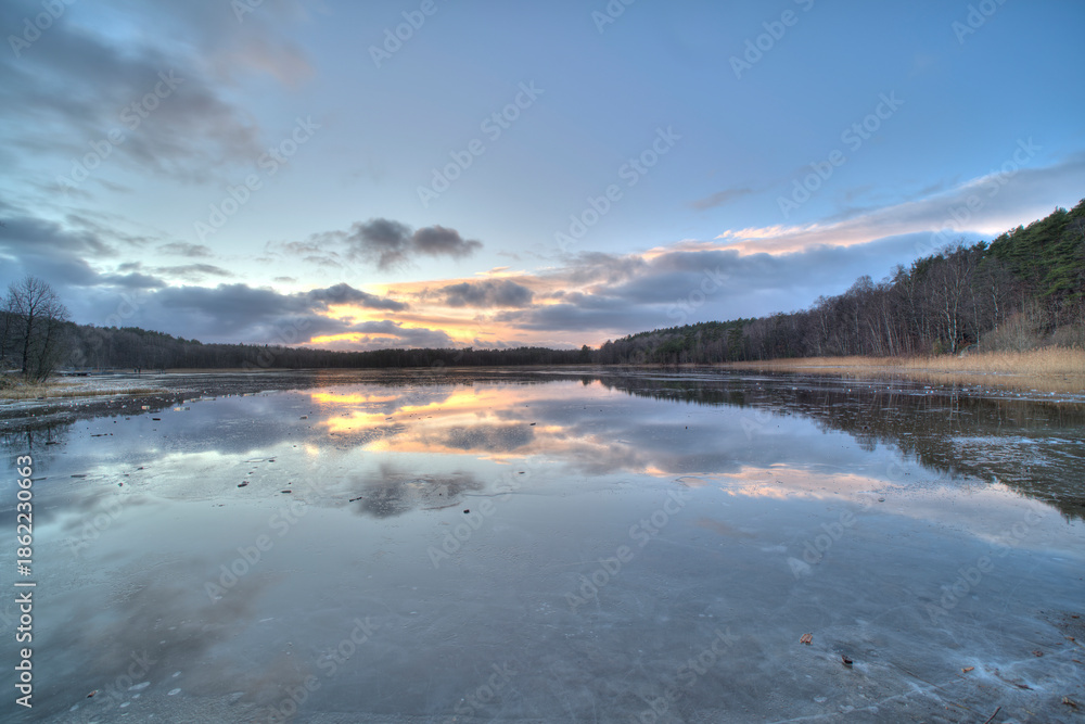 Fototapeta premium Swedish lake surrounded by forest at wintertime.