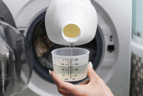Foto Pouring liquid laundry detergent into washing machine drawer