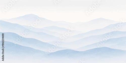 A breathtaking sunrise view of misty blue mountains and clouds blanketing a winter forest valley as the morning sun illuminates the snow covered peak and horizon