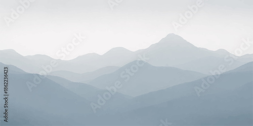 A serene morning mist blankets the mountain landscape as the sun rises over the forest valley, casting a soft haze across the blue hills and snowy horizon under a cloudy sky