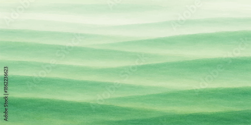 A beautiful summer landscape features a clear blue sky with soft white clouds over a lush green grass field and rolling hills in the rural countryside scenery