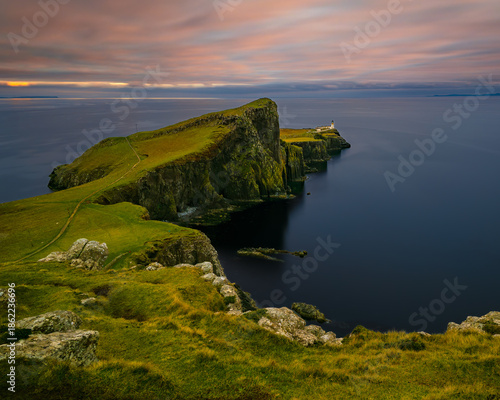 Vertical view of Neist Point cliffs and lighthouse on the Isle of Skye, Scotland, calm ocean and soft clouds creating peaceful coastal landscape with copy space.