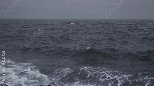 Wide view of a dark and moody ocean with choppy gray waves under an overcast sky during a storm or deep twilight