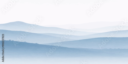 A misty mountain landscape at sunrise features a valley shrouded in fog and clouds under a blue morning sky with snow-capped hills and a lush forest view at the horizon