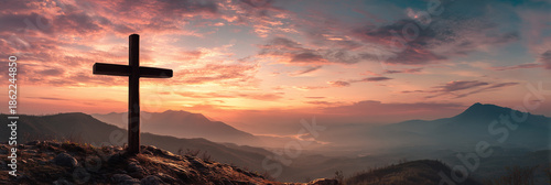 Wooden cross stands on rocky mountain peak at dawn, symbolizing faith and hope with a dramatic sky and tranquil valley vista