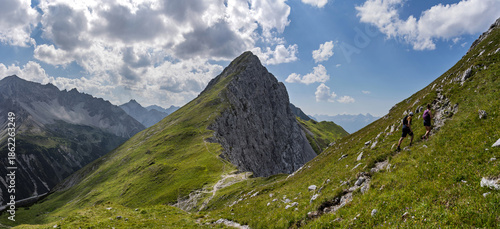 фотографія Two hikers ascend a steep trail toward the summit, with another impressive mountain rising in the background at Maldongrat, Hahntennpass, Tyrol, Austria, alpine scenery