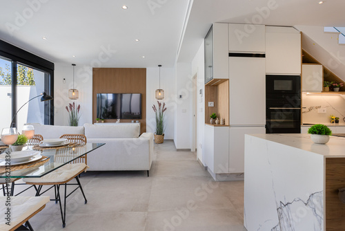 Open concept living room and kitchen with marble island, TV wall, and modern dining setup