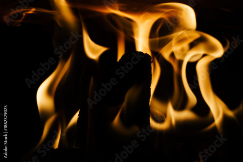 Close-up of a fire in a fireplace, against a black background
