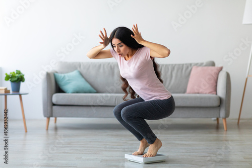 Photos Emotional Indian lady terrified of excess weight, sitting on scales in shock at home, copy space