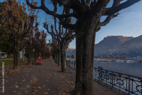 Morning view of promenade in front of lake with the municipal sweeper who collects the leaves. Lugano, Ticino, Switzerland