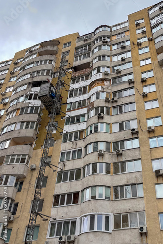 Damage to the facade of a residential building after a drone strike, showing broken windows and debris on the wall.