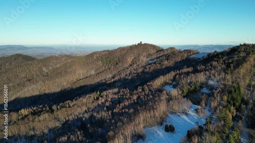 A breathtaking aerial view of a winter mountain landscape in southern Poland, captured by drone above the Koziarz peak in the Małopolska region. The scene showcases a harmonious blend of snow-covered 