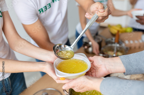 фотографія Young volunteers serve hot soup to those in need at a community charity donation center, working together to alleviate hunger and support the homeless