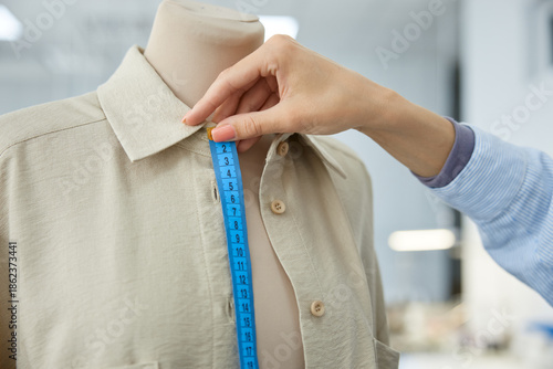 Woman clothing stylist measuring garment for precision in workshop