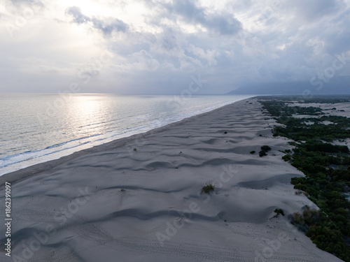 Aerial view of Patara Beach with its golden sand dunes stretch along crystal-clear turquoise water, one of the longest and most unspoiled beaches in Antalya, Turkey.