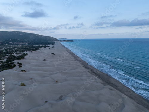 Aerial view of Patara Beach with its golden sand dunes stretch along crystal-clear turquoise water, one of the longest and most unspoiled beaches in Antalya, Turkey.