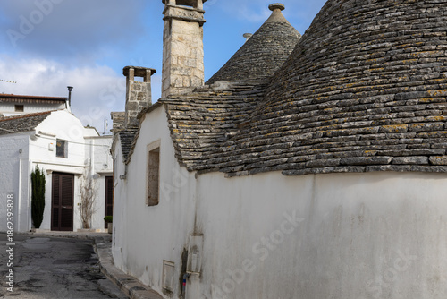 charming street view in alberobello showing iconic white houses with unique stone chimneys and conical roofs under a blue sky in the historic itria valley