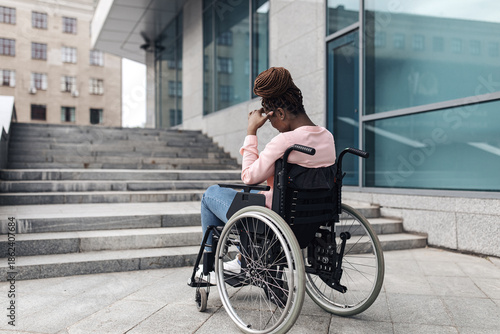 Billede på lærred Unhappy young black woman suffering from lack of wheelchair friendly facilities, cannot get home without ramp, copy space