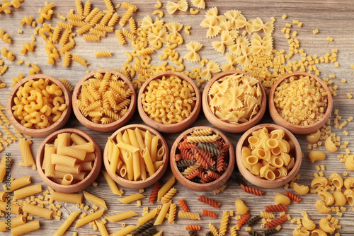 Uncooked pasta varieties,designed in bamboo bowls on a wooden surface.