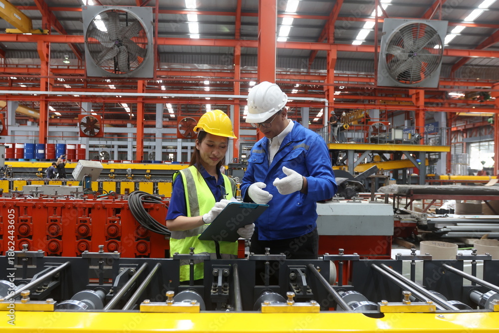 Fototapeta premium Asian new generation of engineer in a metal sheet factory. Studying work methods from supervisors or colleagues. Metal sheet female factory worker and technician male engineer.