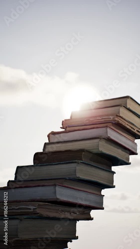 Concept idea stack of books on sky sun set dawn beautiful background. 3D animation. 4K.	
