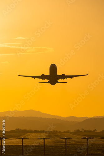 Wallpaper Mural Silhouette of a commercial airplane taking off into a golden sunset sky with mountains Torontodigital.ca