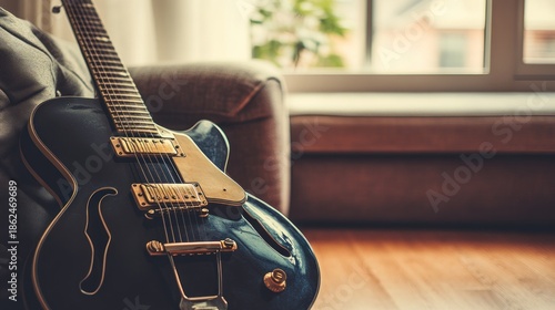 Dark blue electric guitar on couch near window close up