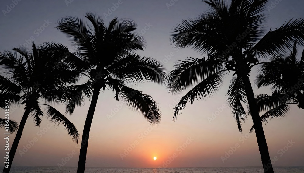 Obraz premium Palm trees silhouette against a vibrant sunset over the ocean