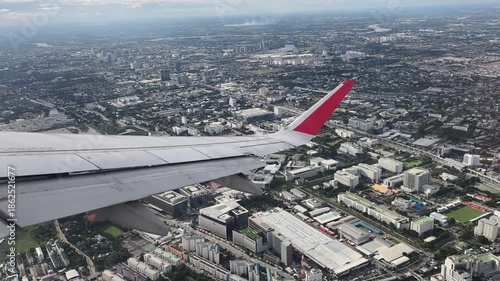 The plane was flying over Bangkok. Aerial view of the Bangkok city the wing tips of the airplane with the clear blue sky.
