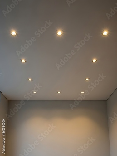 Symmetrical recessed lighting on ceiling illuminating empty room interior