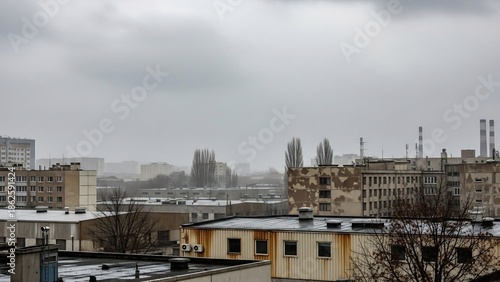 Overcast cityscape view with industrial buildings and distant structures under a cloudy sky.