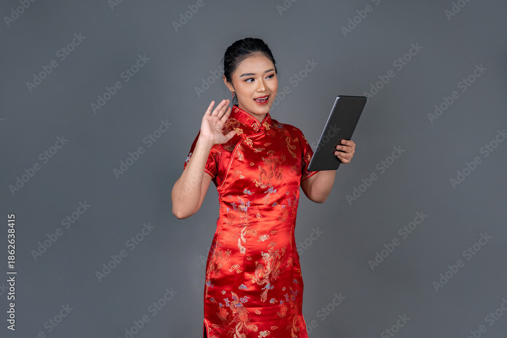 Naklejka premium Modern Asian Woman in Cheongsam Using Digital Tablet