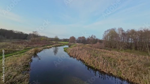 A low and fast drone flight over a river and meadow.