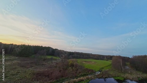 A low and fast drone flight over a river and meadow.