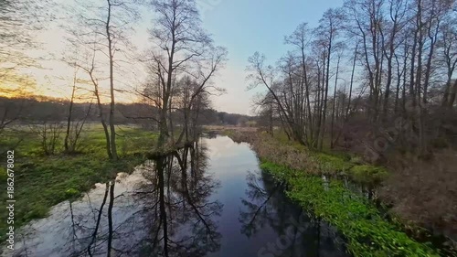 A low and fast drone flight over a river and meadow.