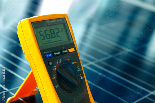 Digital multi meter measuring voltage on solar panel, clean energy concept