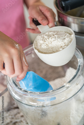 Child Scooping Flour Into Measuring Cup