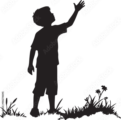 Silhouette of a young boy reaching up to the sky on a grassy patch