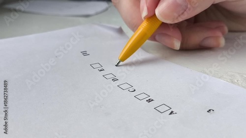 A woman's hand holds a pen and thinks about which answer to choose in the exam test. The process of exams in schools, universities, colleges. Training, education