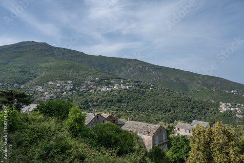 panoramic view village mountainous landscape towards the Gulf of Porto in sunlight with blue skies and spectacular cloud