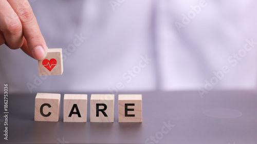 Hand placing wooden block with heart shape on top of others spelling long term medical care showing love and support for healthy life