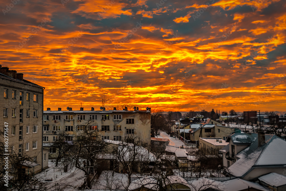 Fototapeta premium Beautiful fire sunset in winter settlement. Amazing orange sky