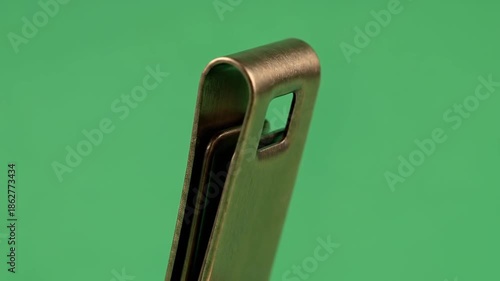 Close-up of a Metal Money Clip on a Green Background.